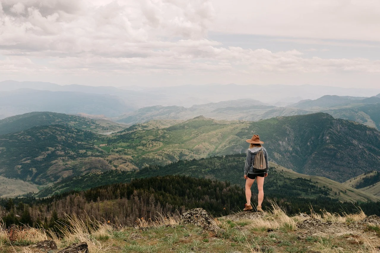 Randonneuse debout sur une crête, face à un panorama de collines et de montagnes